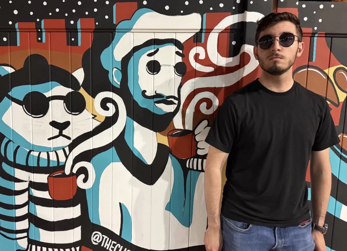 Luca standing in front of a colorful mural